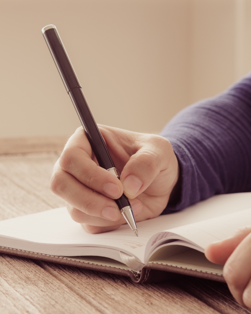 Person schreibt in Notizbuch